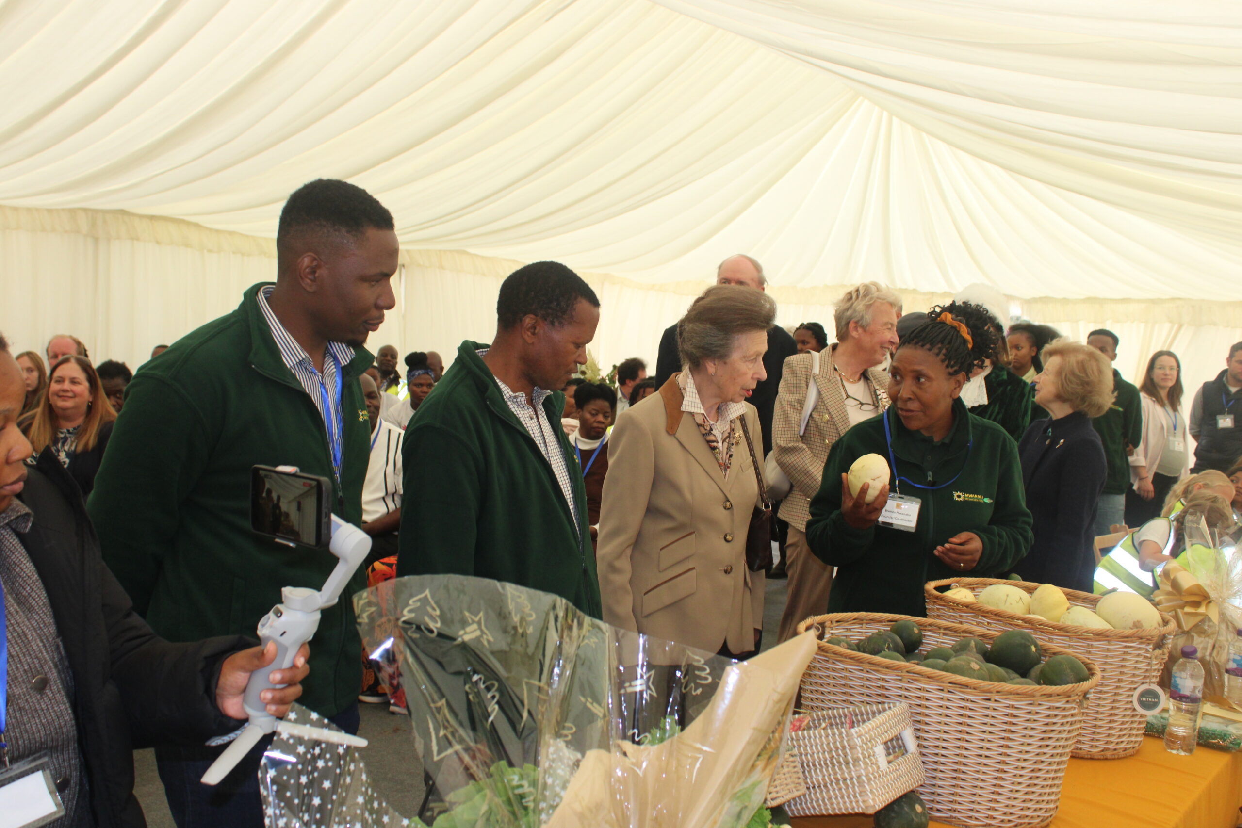 Princess Anne visits Mwanaka Farm in Cambridge, speaking with Mrs Brenda Mwanaka as she presents fresh farm produce, showcasing diaspora farming success and community impact
