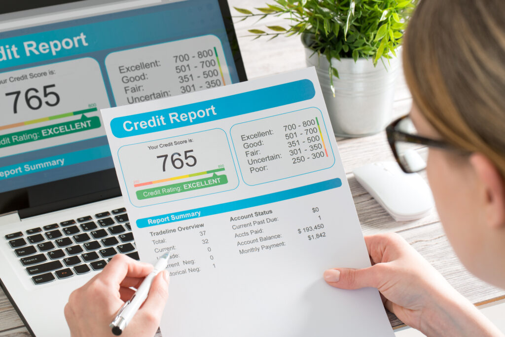 A person reviewing their credit report on a laptop and printed document, illustrating how to build credit abroad and back home.