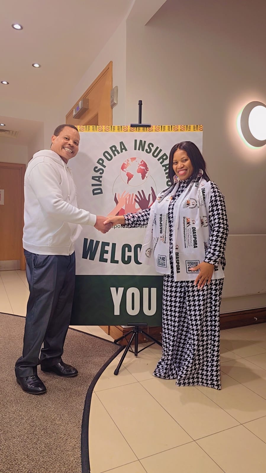 The birth of SACA UK- Diaspora Insurance Jeff Madzingo and sales executive, Heaveny Zulu shake hands beside a Diaspora Insurance welcome banner during the launch of SACA UK.