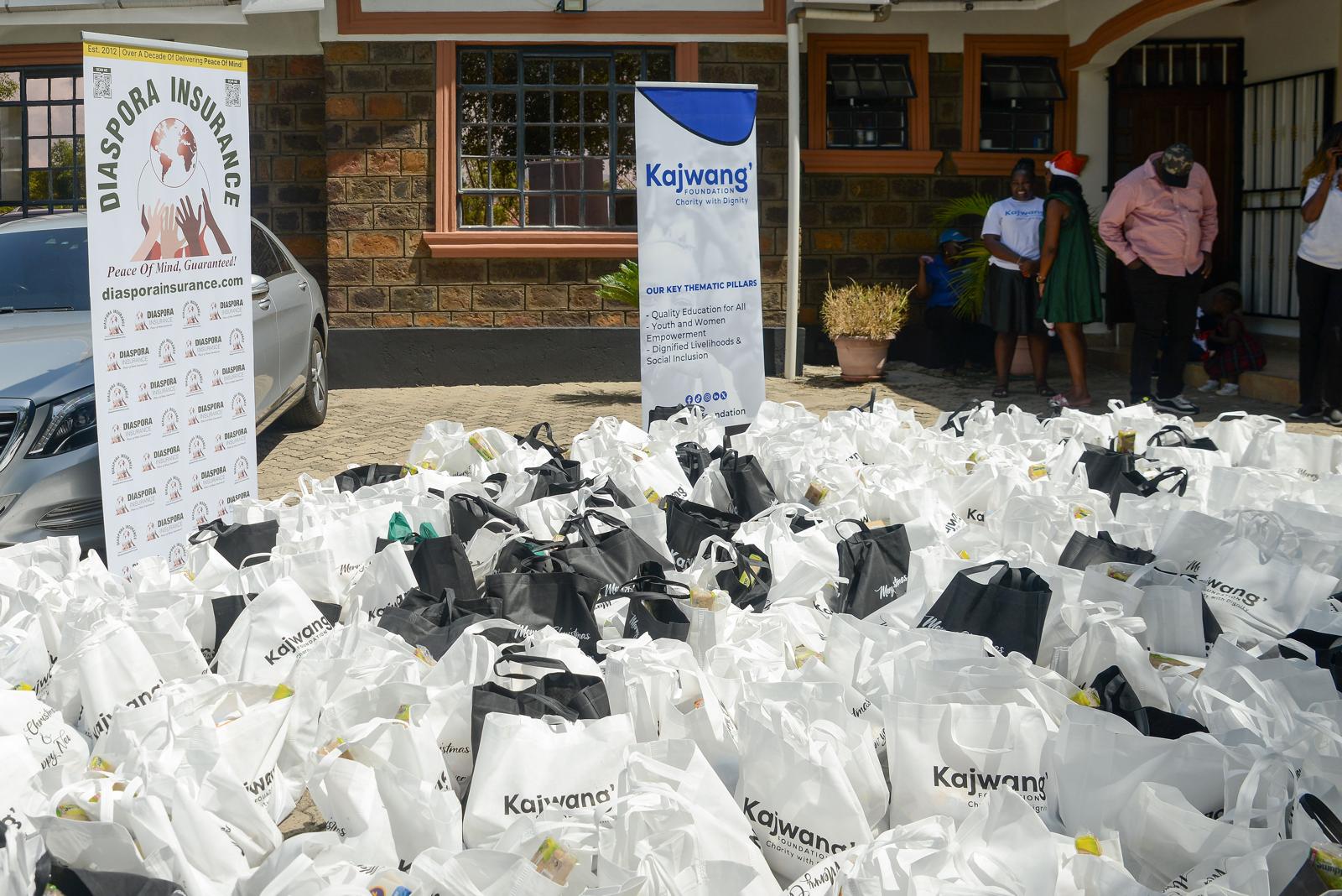 Stacks of bulky food donations, including sacks of grains and packaged goods, awaiting distribution at a Kajwang’ Foundation outreach event in Kenya.
