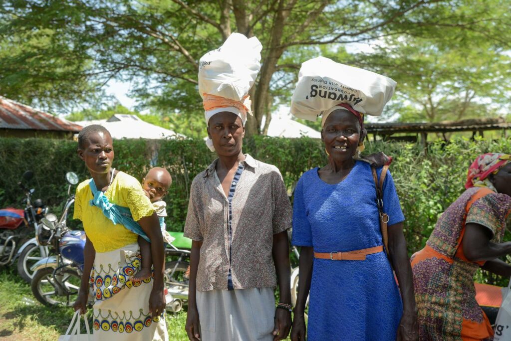 Women from Homabay, Kenya, smiling as they carry donated food supplies home.